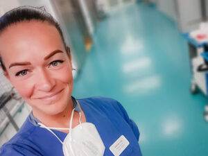 Cindy Kirchhof, Gesundheits- und Krankenpflegerin. Sie ist im Klinik und trägt blauen Kittel