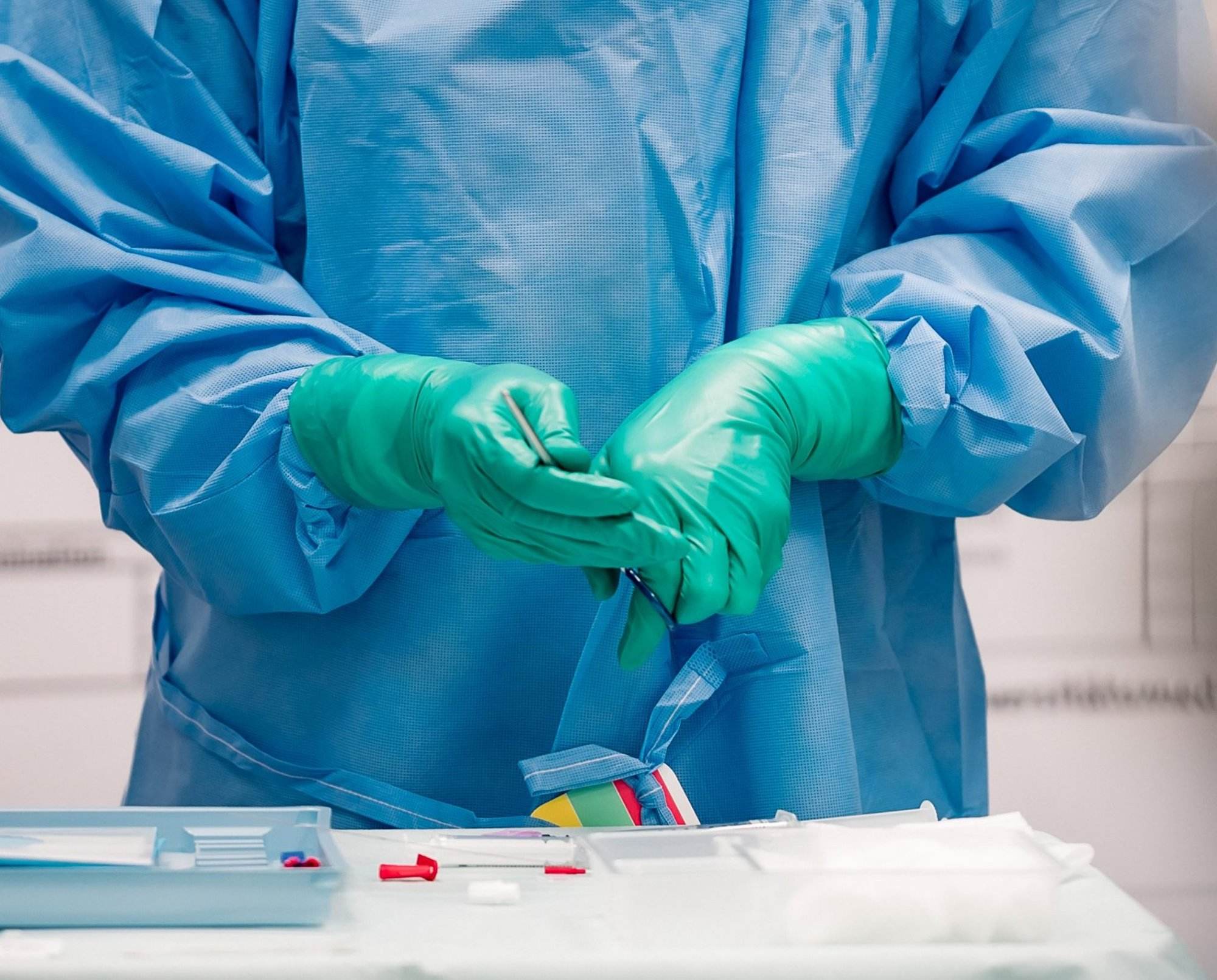 Das Bild zeigt einen Chirurgen in einem OP-Kittel und Handschuhen. Er steht in einem Operationssaal und hält ein chirurgisches Instrument in der Hand.