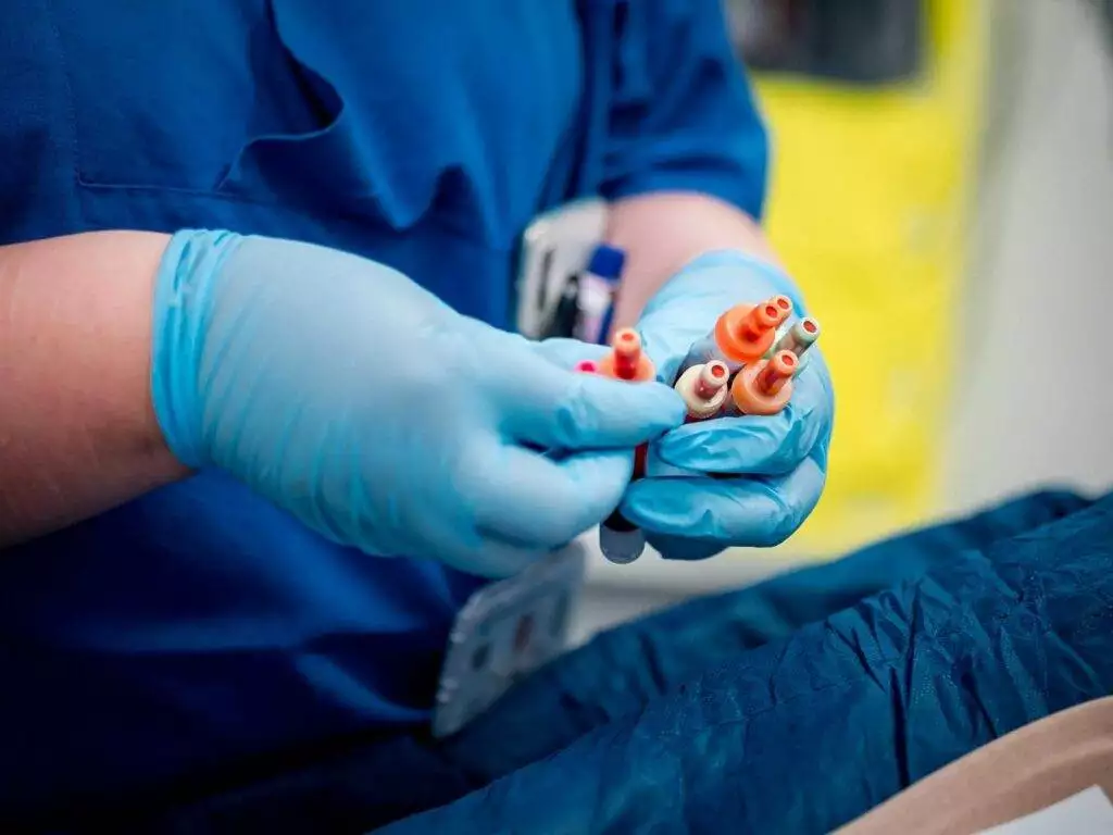 Eine Pflegekraft mit Handschuhen hält mehrere Spritzen in der Hand in einer Klinik.