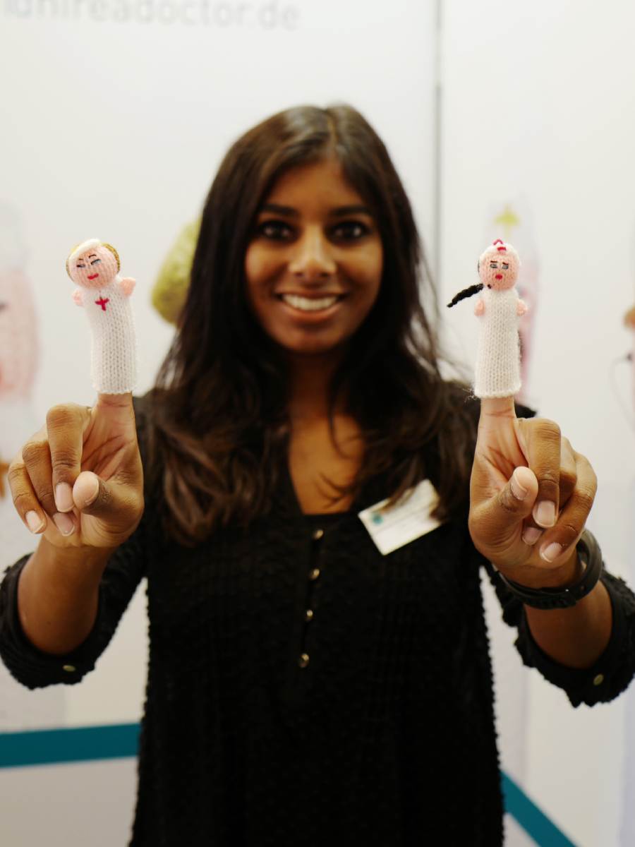 Mitarbeiterin von Hire a Doctor bei einer Fortbildung trägt zwei Fingerpüppchen von Pflegekräften auf ihren Fingern.