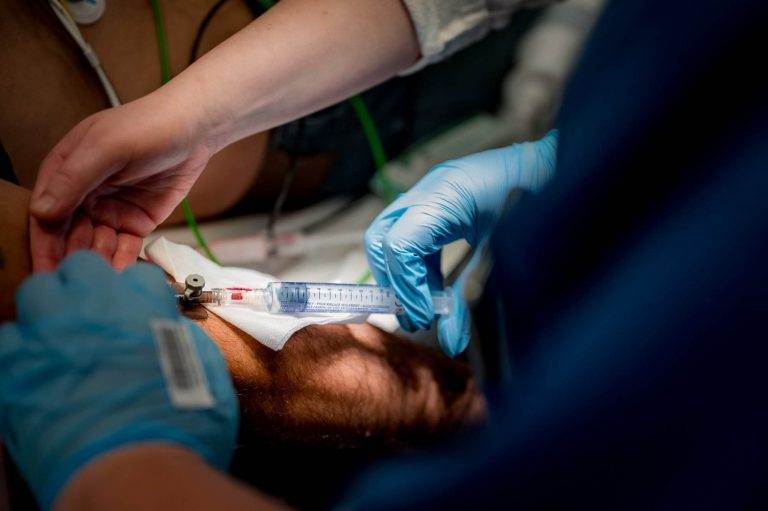 Ein medizinisch-technischer Laboratoriumsassistent (MTLA) mit Handschuhen hält eine Spritze zur Blutentnahme bereit.